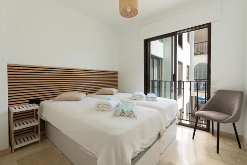 a white bedroom with two beds and a chair at 327 marina duquesa in Manilva