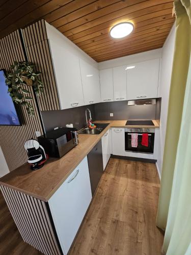 a kitchen with white cabinets and a wooden ceiling at Peak Apartment - Aare Jungfrau AG in Grindelwald