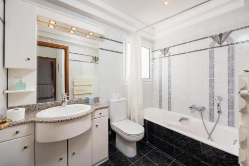 a white bathroom with a sink and a toilet and a tub at Villa Sunset Paradise in Kalavárda