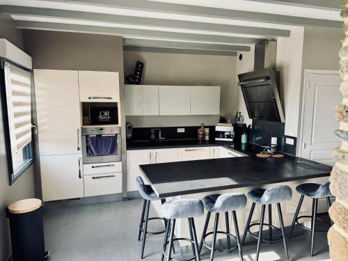 - une cuisine avec une table et des tabourets dans l'établissement La parenthèse du Mont, à Ducey