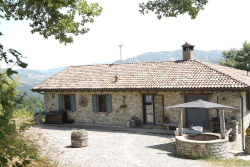 a stone house with an umbrella in front of it at Holiday appartment Casa del Cervo in Sestola