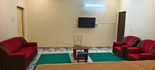 a waiting room with two red chairs and a tv at Sri Arunachalam Residency in Tiruvannāmalai