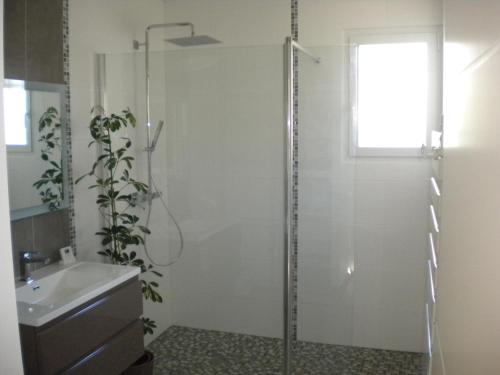 uma casa de banho com um chuveiro e um lavatório. em Nokanhui em Soulac-sur-Mer