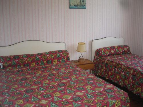 une chambre avec deux lits et une table avec une lampe dans l'établissement Les Ajoncs, à Mimizan