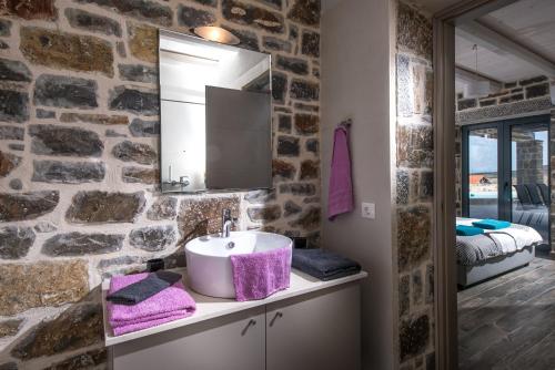 uma casa de banho com um lavatório e uma parede de pedra em Anna Luxury Villa Cretevasion em Kokkíni Khánion