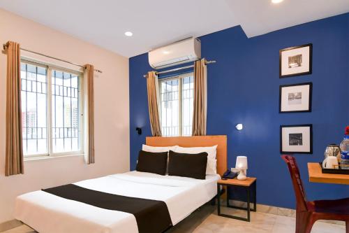 a bedroom with blue walls and a bed and a desk at Super Collection O Bisarjan Ghat Formerly Eden Rocks in Kolkata
