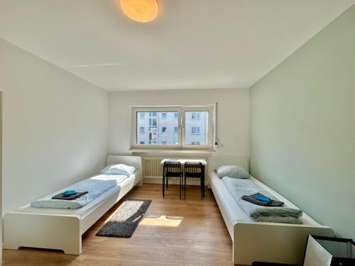 2 camas en una habitación con mesa y ventana en Family Apartments Near City Centre, en Frankfurt