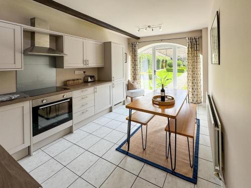 a kitchen with white cabinets and a table with chairs at Farmhouse Feels & Peak Views in Pott Shrigley