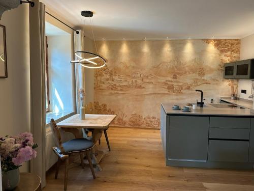 a kitchen with a table and a wall with a painting at Aparthotel Ansitz Felsenheim in Lermoos