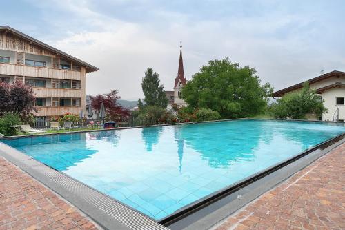 a large blue swimming pool in front of a building at Residence Nussbaumer in Siusi