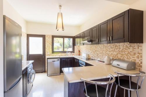 a kitchen with black cabinets and a stainless steel refrigerator at Villa Fortuna in Polis Chrysochous