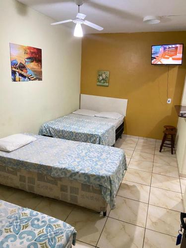 a room with two beds and a flat screen tv at Pousada Cantinho da Nilza in Cabo Frio
