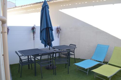 une table, deux chaises et un parasol dans l'établissement Le Gravelot Royannais, à Royan