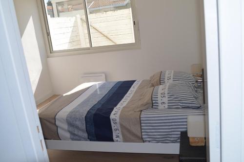 un lit dans une petite pièce avec une fenêtre dans l'établissement Le Gravelot Royannais, à Royan