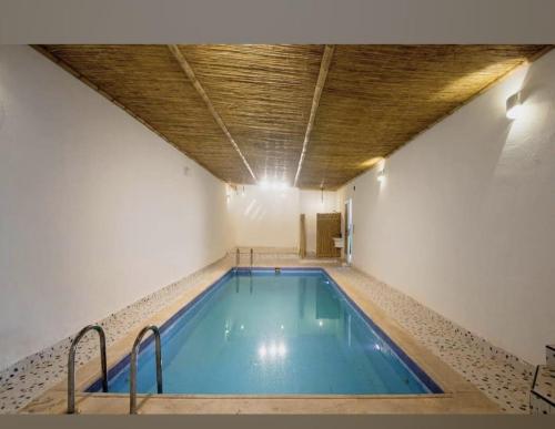 a swimming pool in a building with a wooden ceiling at منتجع بامبو in Quşūr al Muqbil