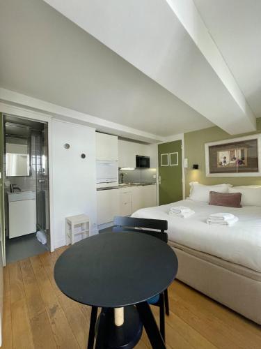 une chambre avec un lit et une table et une cuisine dans l'établissement PARISIAN HOME l BELLAN, à Paris
