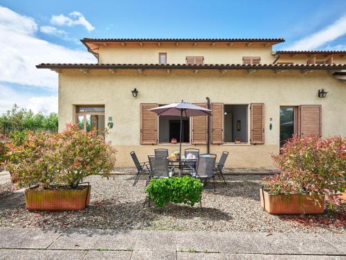 a table and chairs with an umbrella in front of a house at Casa Vacanze Santa Caterina in Asciano