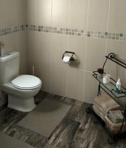 a bathroom with a toilet and a shelf with towels at Cottage on Long in Montagu