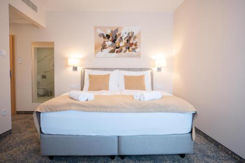 a bedroom with a large bed with two towels on it at Kikelet Club Hotel in Miskolctapolca
