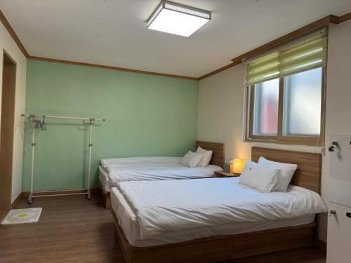 two beds in a room with a window at Suncheon Doran Doran House in Suncheon