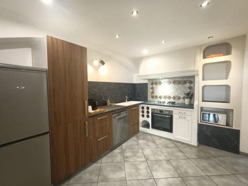 une grande cuisine avec des appareils électroménagers blancs et des armoires brunes dans l'établissement Maison de ville 3 chambres climatisées, à Bourg-Saint-Andéol
