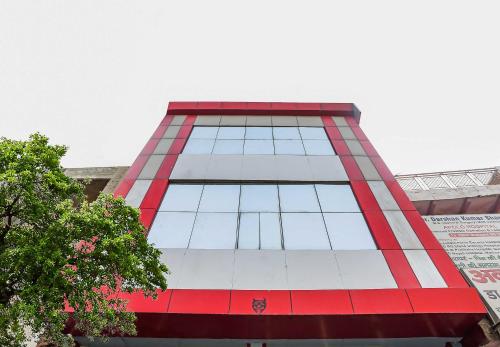 a tall red and white building with glass windows at Hotel O Gold Stayz in Ballabgarh
