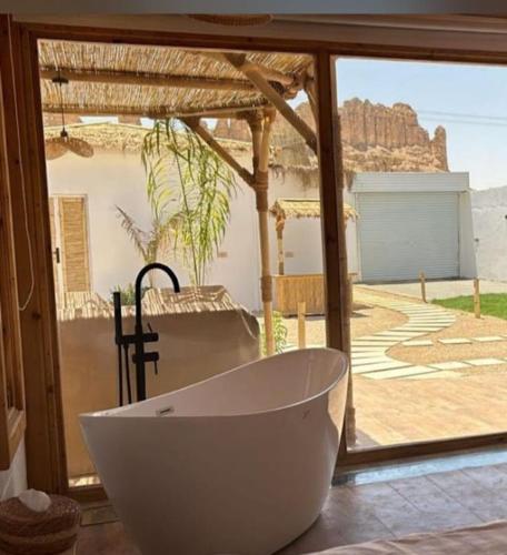 a bath tub in front of a window with a view at منتجع بامبو in Quşūr al Muqbil