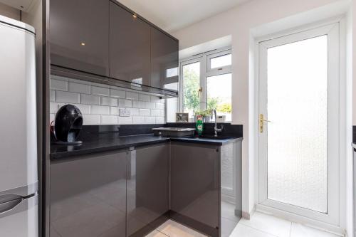 a kitchen with black counters and a large window at West Green House Spacious 3BR Parking Next to Crawley Hospital in Ifield