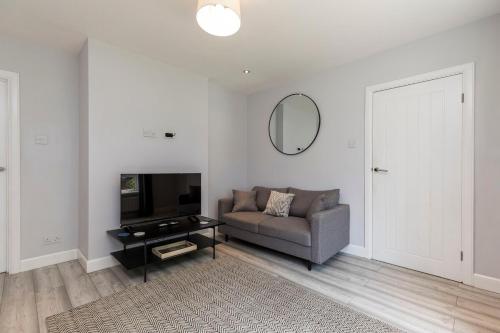 a living room with a couch and a mirror at West Green House Spacious 3BR Parking Next to Crawley Hospital in Ifield