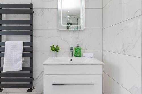 a white bathroom with a sink and a mirror at West Green House Spacious 3BR Parking Next to Crawley Hospital in Ifield