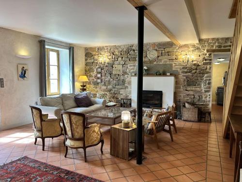 un salon avec un canapé et un mur en pierre dans l'établissement 210 - Maison de caractère pour 10 convives, à Plurien