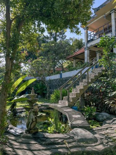 a garden with a pond in front of a house at Dejaviews Resort in Singaraja