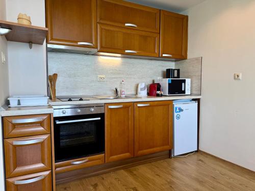 a kitchen with wooden cabinets and a white refrigerator at Cosher - Gardenia Palace Apt 10 Free Parking in Pomorie