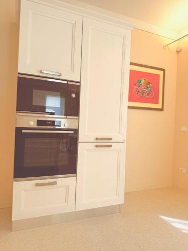 a kitchen with white cabinets and a microwave at Casa Edvige Suite in Monteveglio