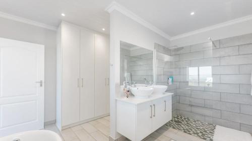 a white bathroom with two sinks and a shower at Pondok Straat - Agulhas in Agulhas