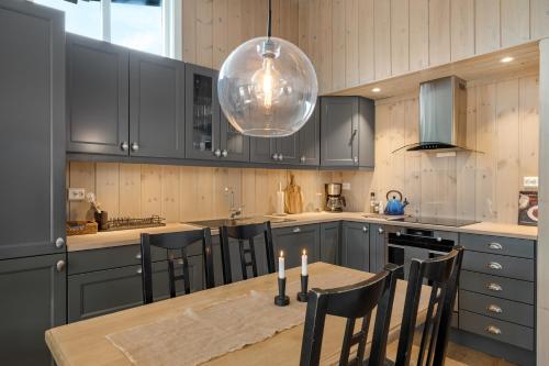 a kitchen with a table with chairs and aandelier at Bitigrenda M in Beitostøl