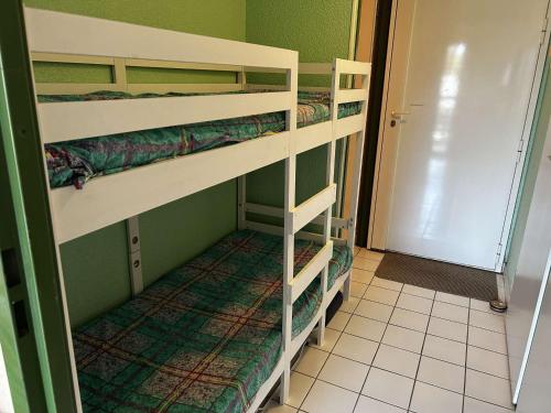 Ce dortoir comprend 2 lits superposés et une porte. dans l'établissement Appart 2 pièces avec piscine et parking à Port Camargue - FR-1-250-293, au Grau-du-Roi