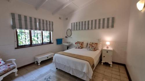 a white bedroom with a bed and a window at 26 Marion Road in Ballito