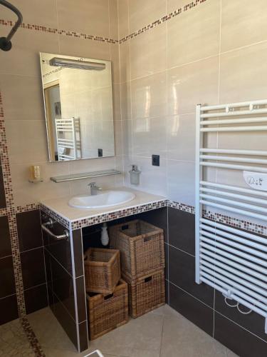 La salle de bains est pourvue d'un lavabo, d'un miroir et de paniers. dans l'établissement Villa La Tramontane, à La Valette-du-Var