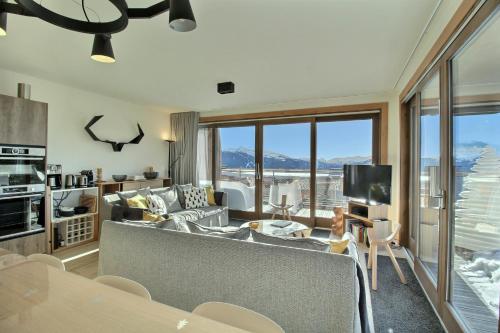 un salon avec un canapé et une télévision dans l'établissement ARC 1600, LE RIDGE, Appartement 12 personnes Duplex Vue Montagne - ski aux pieds - Sauna, Hammam, Jacuzzi, Piscine, à Arc 1600