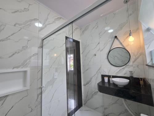 a bathroom with a shower with a sink and a mirror at Ótimo apartamento, charmoso e arejado in Nova Friburgo