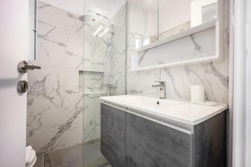 a white bathroom with a sink and a shower at Varkizaki by the sea in Varkiza
