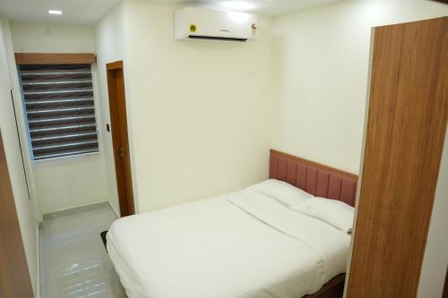 a small bedroom with a white bed and a window at Theeram Residency in Iringal