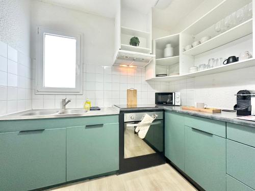 une cuisine avec des armoires bleues et un évier dans l'établissement LE COSY - Plain-Pied, à Mont-de-Marsan