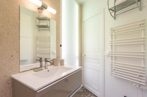une salle de bain blanche avec un lavabo et un miroir dans l'établissement C10 - 3P 10 min Palais Festivals & Sea - AC & Parking, à Cannes
