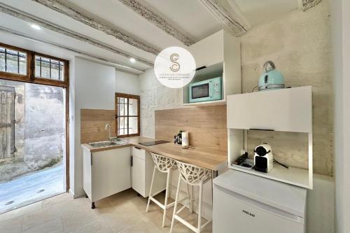 une cuisine avec des armoires blanches et un comptoir dans l'établissement La Petite Bulle Arles Center, à Arles