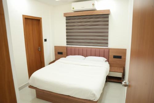 a bedroom with a white bed with a wooden headboard at Theeram Residency in Iringal