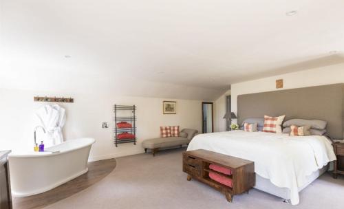a bedroom with a large bed and a bath tub at Anvil Cottage in Grewelthorpe