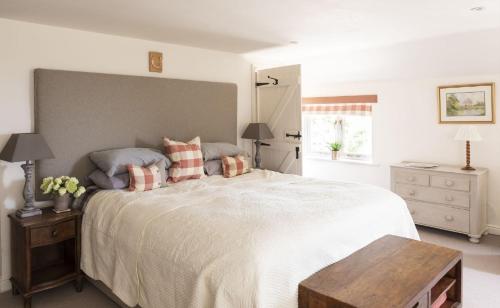 a bedroom with a large white bed with pillows at Anvil Cottage in Grewelthorpe