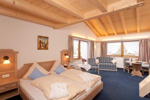 Schlafzimmer mit einem Bett, einem Schreibtisch und Stühlen in der Unterkunft Hotel Landhaus Feldmeier ***S in Oberammergau